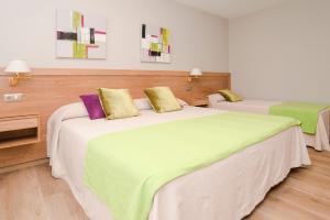 桑亨霍卡里布萨克森酒店的一间卧室配有两张带绿色和紫色枕头的床