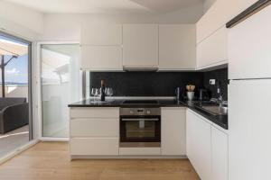 安卡兰Apartments ERA Ankaran的厨房配有白色橱柜和炉灶烤箱。