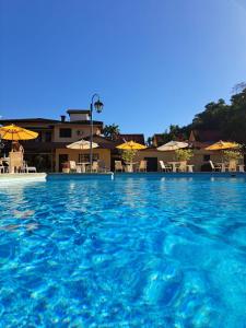 佩尼多Hotel Girassol的一座带蓝色水和遮阳伞的大型游泳池