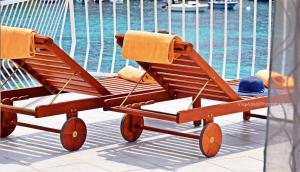 莫鲁纳特Villa Ana Apartments的一张木制沙滩椅,上面有帽子,位于游泳池旁