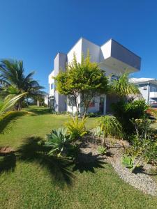 普莱亚塞卡Casarão de frente para a lagoa de Praia Seca的白色的房子,有植物的院子