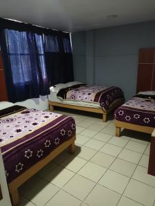墨西哥城HOTEL PUERTO MEXICO 2的一间设有三张床的客房,配有紫色的床单