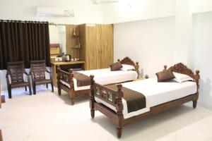 蒂鲁奇奇拉帕利Indian Residency的一间卧室配有两张床和一张桌子及椅子
