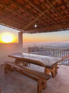 圣托梅-达斯莱特拉斯Casa Por do Sol.的阳台上的大型木制野餐桌,享有日落美景