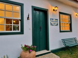 蒂拉登特斯Lofts Villa da Serra的白色房子的绿色门,带长凳