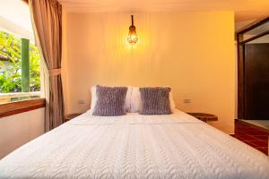 CalabazoPortales del Tayrona Garden Hotel的卧室配有带枕头的白色床和窗户。
