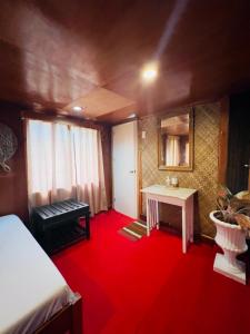 道伊斯Bohol Island Homestay的一间铺有红地毯的带一张床和一张桌子的房间