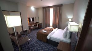 埃尔比勒班诺酒店的配有一张床和一把椅子的酒店客房
