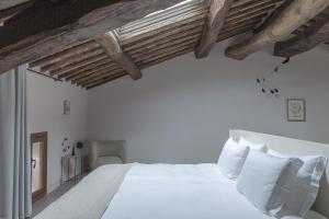 拉达-因基安蒂Pieve Aldina Relais & Châteaux的卧室设有白色的床和木制天花板。