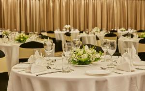德瓦纳哈利-班加罗尔招牌俱乐部度假村 的用餐室配有白色的桌椅和白色的鲜花