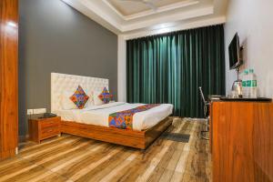 古尔冈FabHotel Skylight Inn Near Medanta Hospital的一间卧室配有床和绿帘