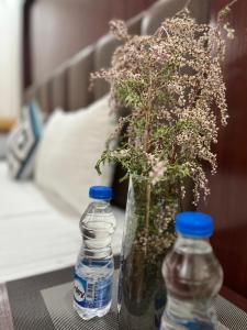列城Ladakh Country Inn的2瓶水和1个带鲜花的花瓶(桌子上)