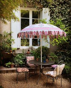 CoursanLe logis blanc bed&breakfast的房屋前带粉红色伞的桌子