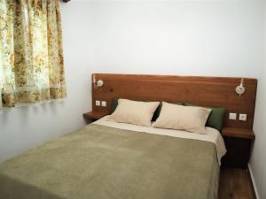 基斯诺斯ΤΟ ΚΑΜΙΝΙ ΤΟΥ ΜΗΛΑ的一间卧室配有一张带木制床头板和窗帘的床。