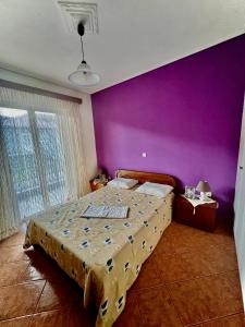 KaryesKolovos House的一间卧室配有一张大床和紫色墙壁