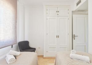 米哈斯科斯塔Marina XI Lovely apartment inside Wyndham Resort的白色卧室配有两张床和椅子