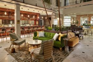 加尔维斯敦The Tremont House, Galveston, a Tribute Portfolio Hotel的大堂设有绿色的沙发和椅子,酒吧
