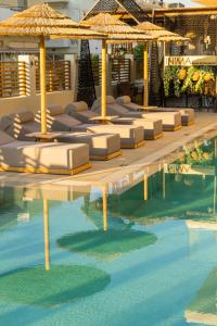卡尔扎迈纳Cabana Blu Hotel & Suites的游泳池里一排带遮阳伞的躺椅