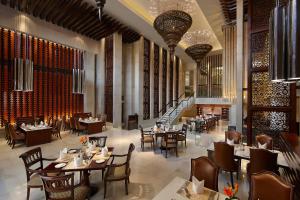 阿格拉ITC Mughal, A Luxury Collection Resort & Spa, Agra的一间带桌椅的餐厅,以及楼梯