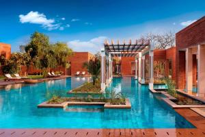 阿格拉ITC Mughal, A Luxury Collection Resort & Spa, Agra的蓝色建筑中的游泳池