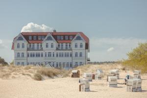 塞巴特阿尔贝克Strandhotel Ostende的海滩上一座大建筑,沙滩上摆放着椅子