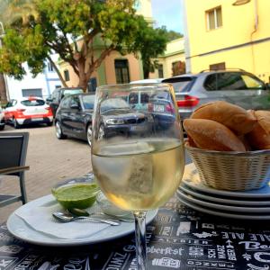 San AndrésSan Andres Beach View Apartment的坐在桌子上边,一边享用一杯白葡萄酒,一边品尝面包