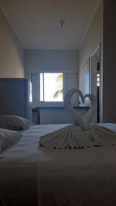 伊塔尼亚恩Hotel Pousada Miami的两个天鹅在床上形成心