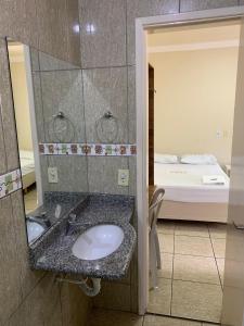 戈亚尼亚Pissin Plaza Hotel的一间带水槽和镜子的浴室以及一张床