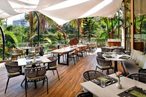 内罗毕内罗毕胡尔林汉福朋喜来登酒店的一间设有桌椅和树木的餐厅