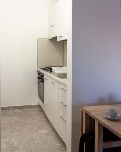 圣维托诺曼Nopal casa vacanze的厨房配有白色橱柜和木桌