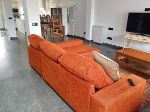 桑坦德Casa San Miguel 93 santander的客厅里一张橙色的沙发,配有电视