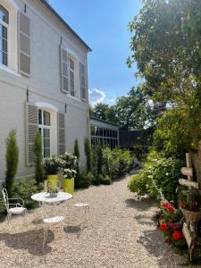 蒙特勒伊Aux remparts de Montreuil的房屋前设有带桌椅的花园