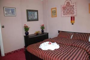 盖尼特拉Ambassy Hotel的一间卧室配有一张带红色和白色棉被的床