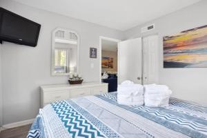 希尔顿黑德岛5 stars Peaceful Condo - 7 min walk to the beach的一间卧室配有带枕头的床和电视。