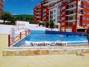 埃勒尼特Apartament Sea Fort Club Grand Resort Fort Noks Sveti Vlas-Bastet BS的一个带椅子的游泳池,水中有人