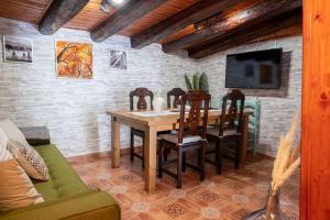 佩德罗－贝尔纳多Casa Rural El Burrito de Gredos的一间带桌椅和电视的用餐室