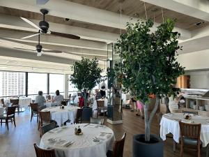 檀香山Serenity Waikiki ! Luxury Ocean Suite !的一间设有白色桌子和大植物的餐厅