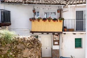 佩德罗－贝尔纳多Casa Rural El Burrito de Gredos的阳台上的白色房子,鲜花盛开