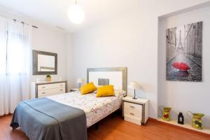 阿尔蒙特Cómodo apartamento en Almonte的一间卧室配有一张带黄色枕头和红色遮阳伞的床。