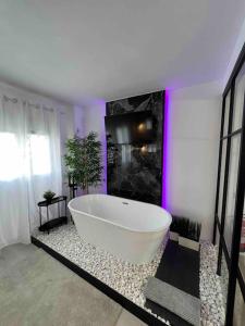马德里Apartamento marqués的浴室内设有一个大型白色浴缸,拥有紫色的灯光