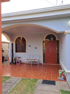 马那瓜Acogedora Casa的一座房子,设有红色的门,在庭院里设有长凳