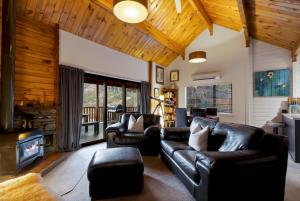 皇后镇Kereru Cottage, Romantic & Beautiful Log Cabin - Queenstown的客厅配有皮革家具和壁炉