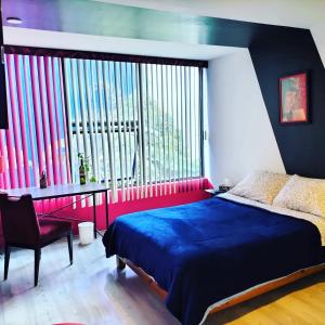墨西哥城Casa Maguey的一间卧室配有一张床、一张书桌和一个大窗户
