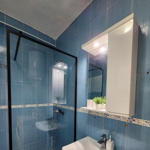 地拉那Cozy sunlit apartment with scenic balcony view的蓝色的浴室设有水槽和镜子