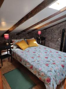 托尔明Casa di Volce - 1801 Stone House的一间卧室配有一张带花卉毯子和两盏灯的床。