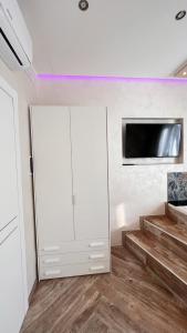 奇维塔韦基亚Suites Matteotti 57的一间设有白色橱柜和墙上电视的房间