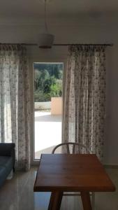 波塔莫斯AVRA-2 Apartments Potamos CORFU的客厅设有木桌和大窗户。