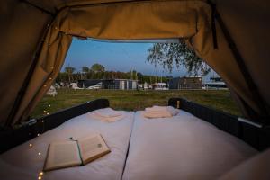 萨斯尼茨Marina Martinshafen - Beach life的帐篷内的一张床位,上面有一本书
