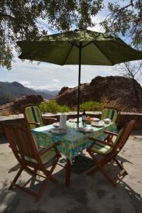 克鲁兹·德·特赫达Casa Cueva El Pedregal Tejeda的一张桌子、两把椅子和一把绿色雨伞