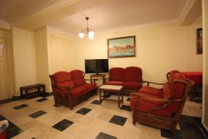 阿尔及尔Hotel Hydra的一间设有红色椅子和平面电视的等候室